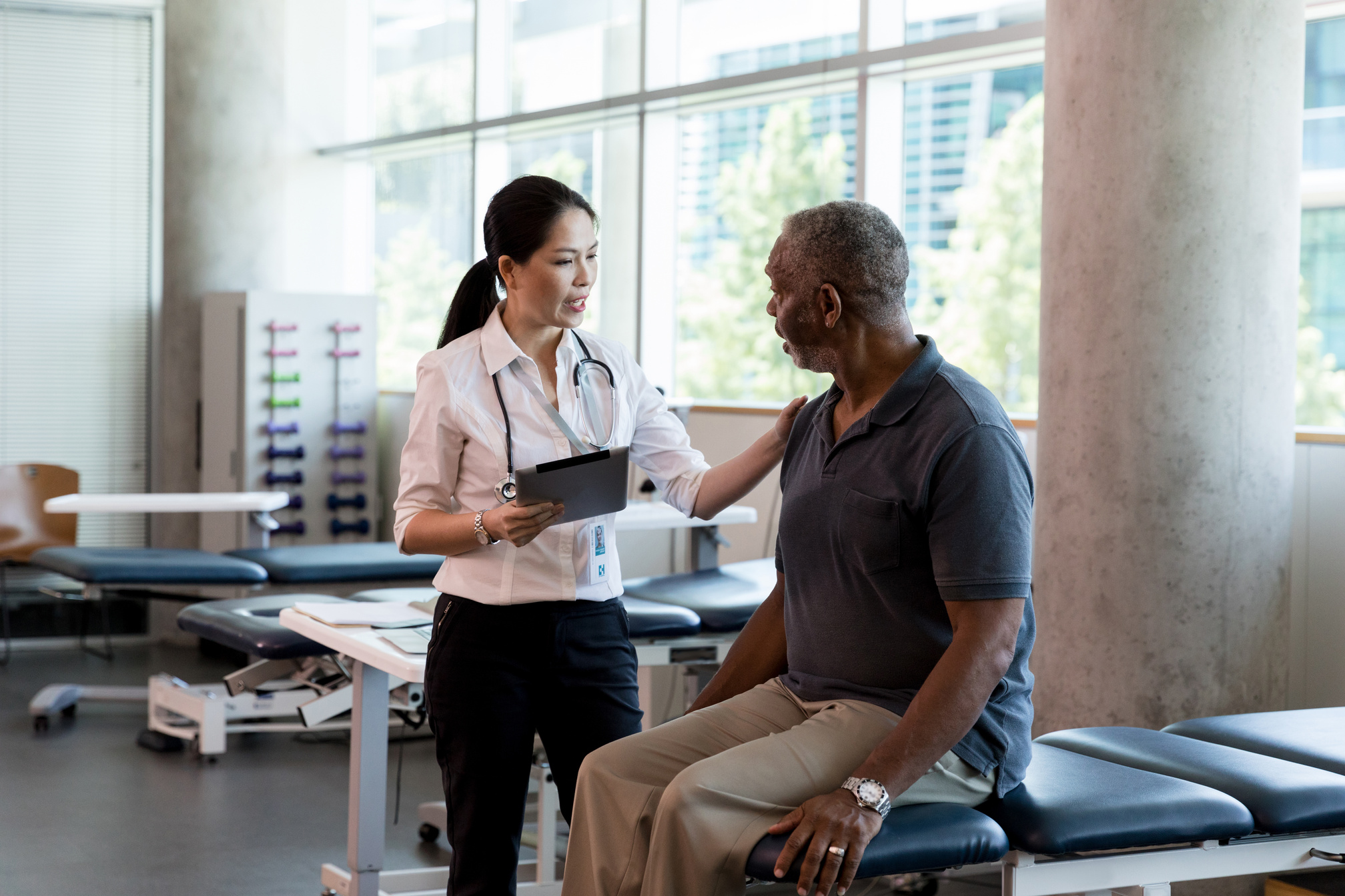 Female physical therapist assesses a mature adult male patient